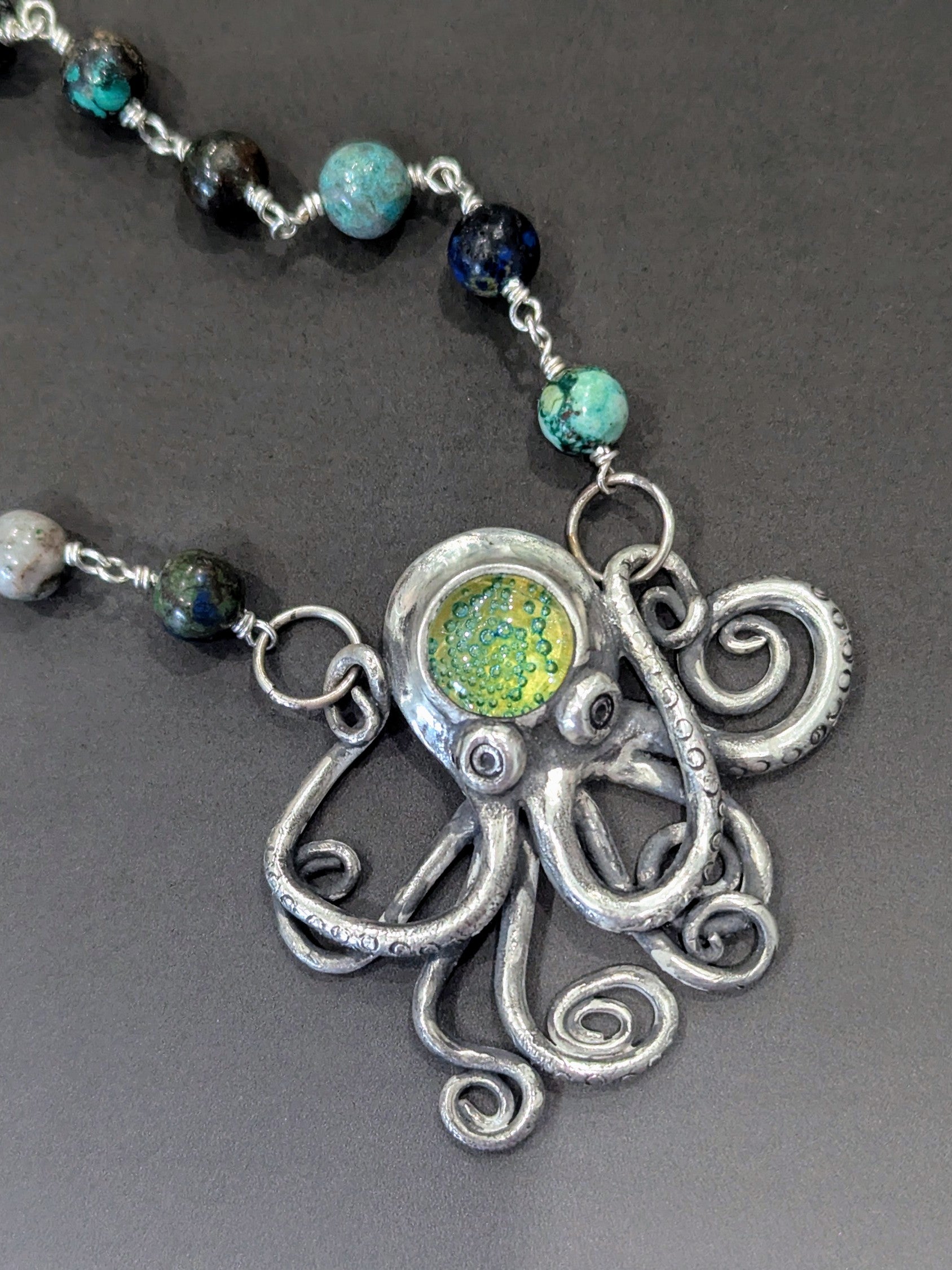 Necklace with an octopus pendant and beaded chain on a gray background