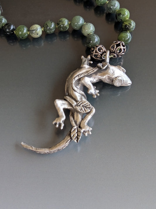 Necklace with silver lizard pendant and green beads on a gray background