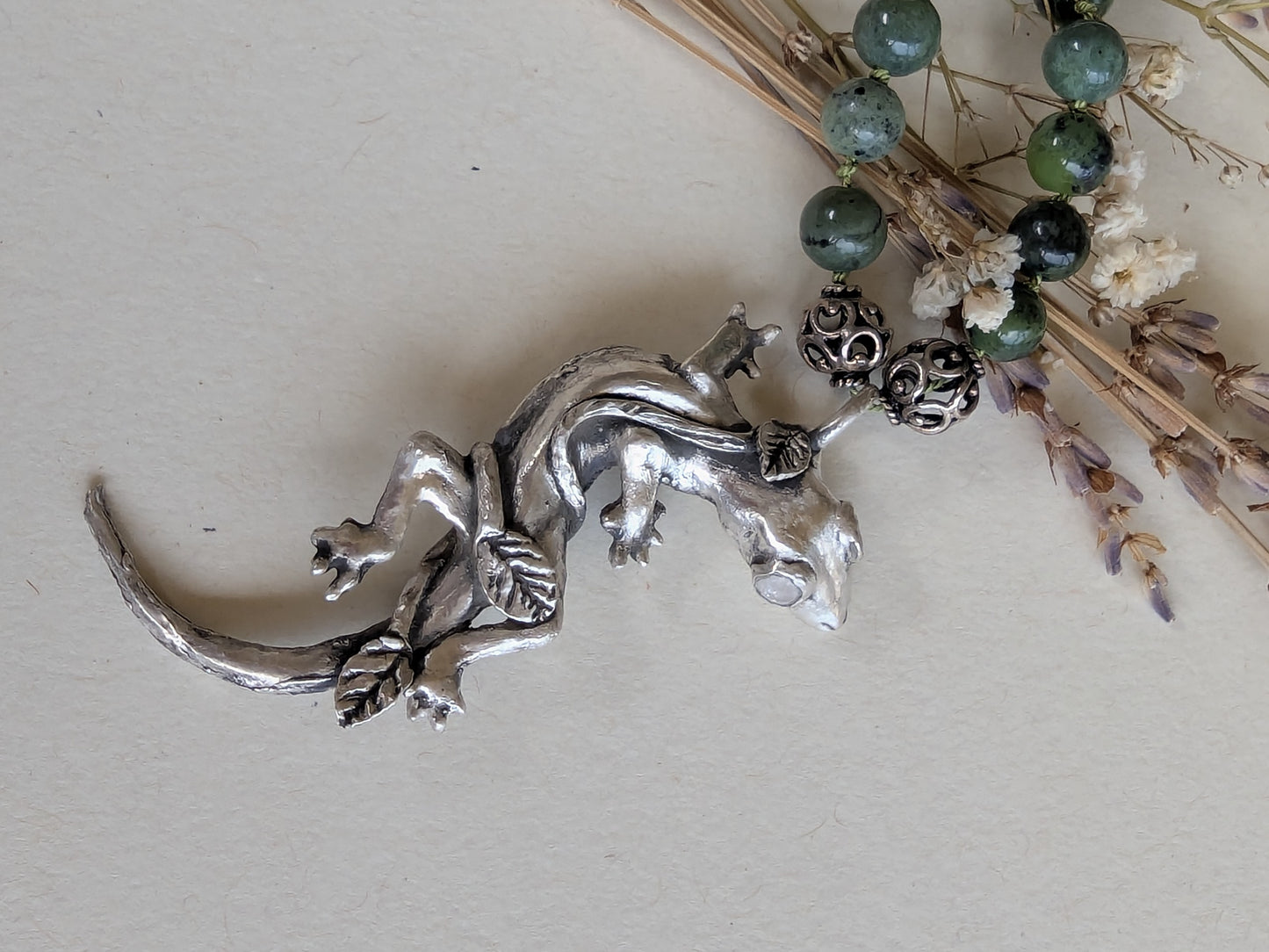Silver lizard-shaped pendant on a light background
