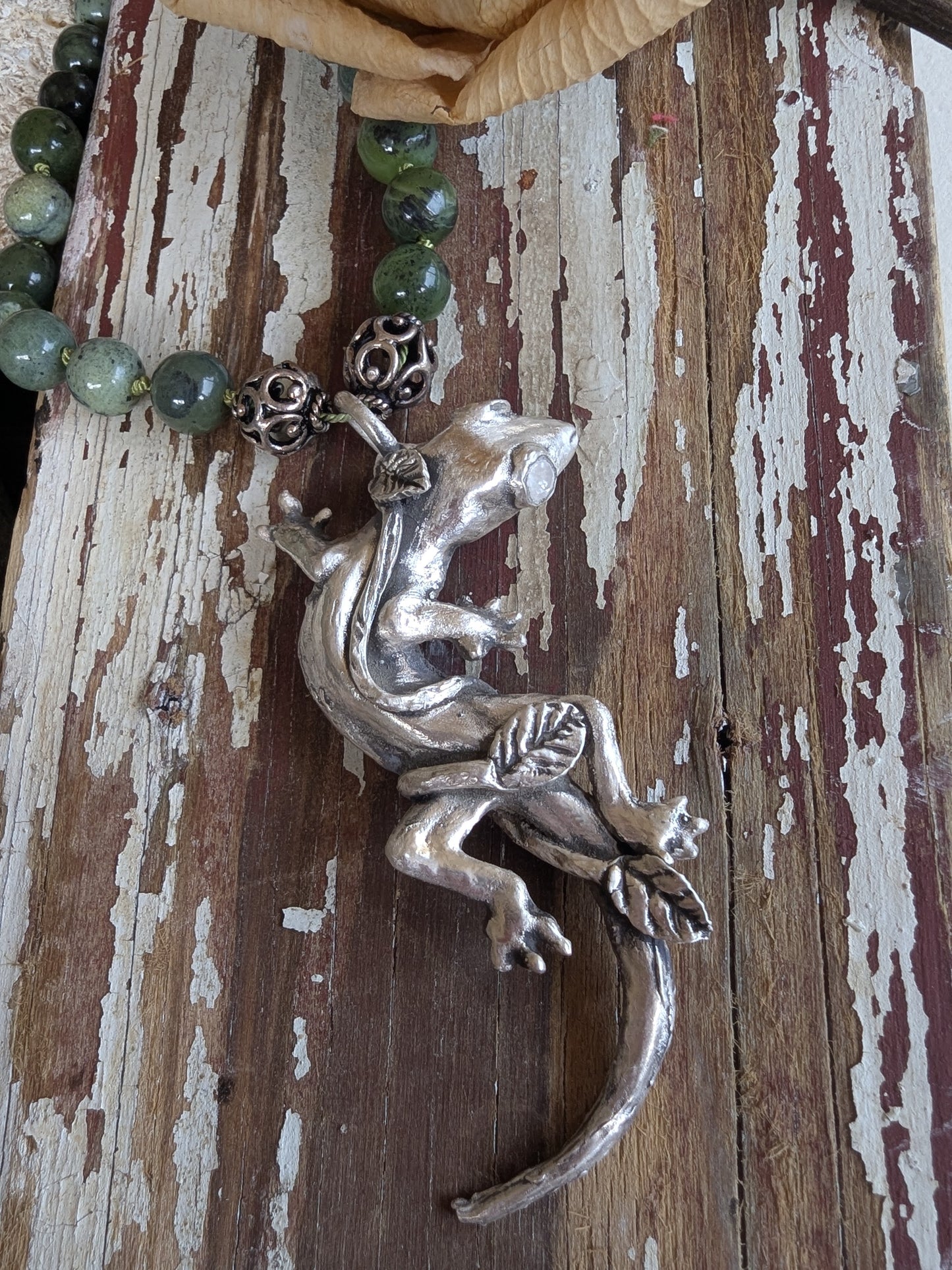 Silver lizard pendant on a wooden surface