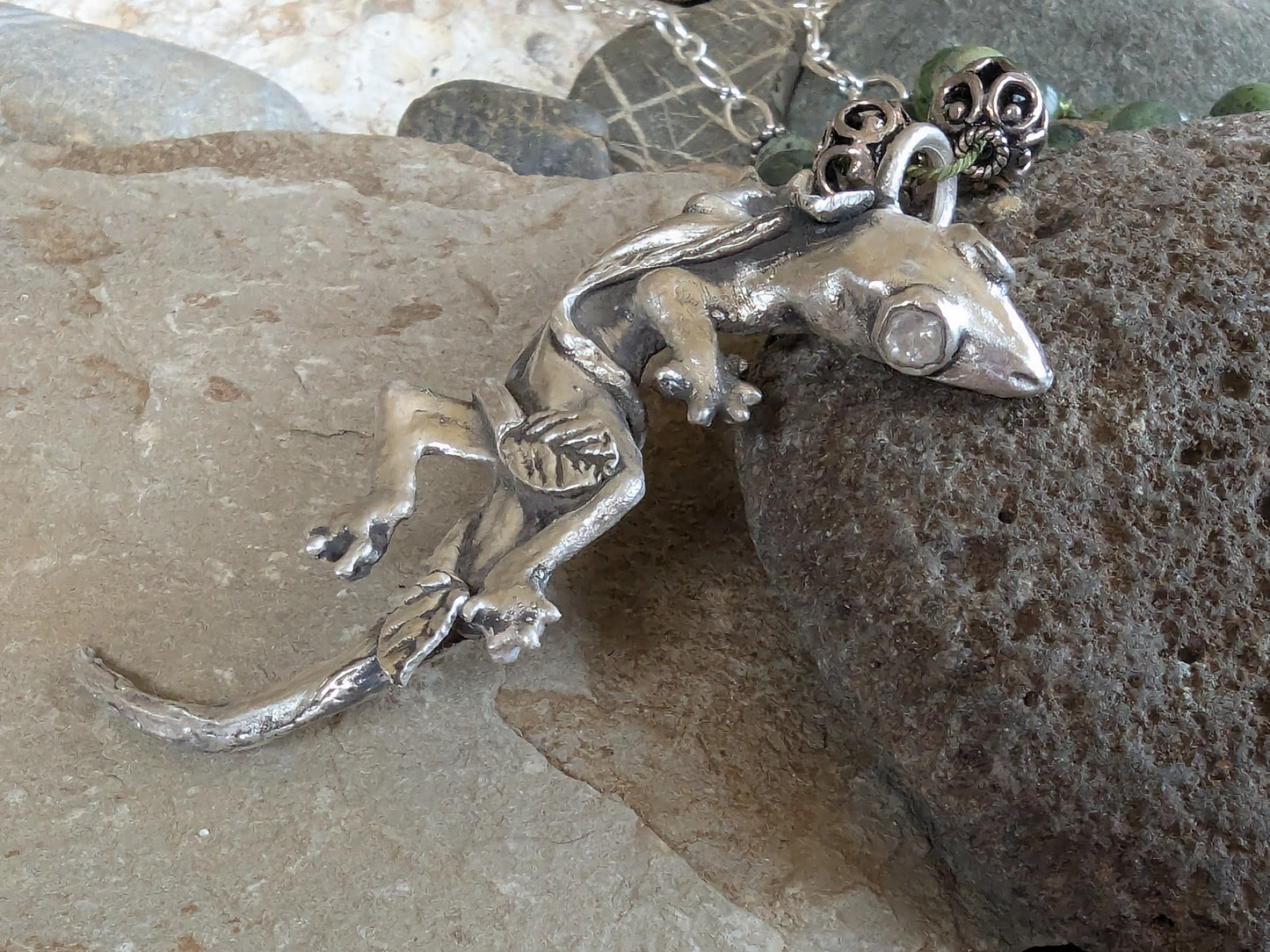 Silver lizard pendant on a rocky surface
