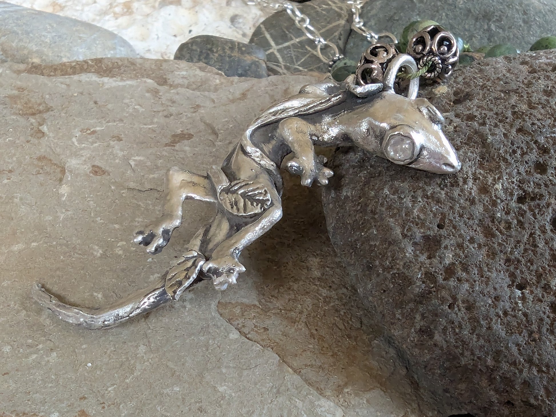 Silver lizard pendant on a rocky surface