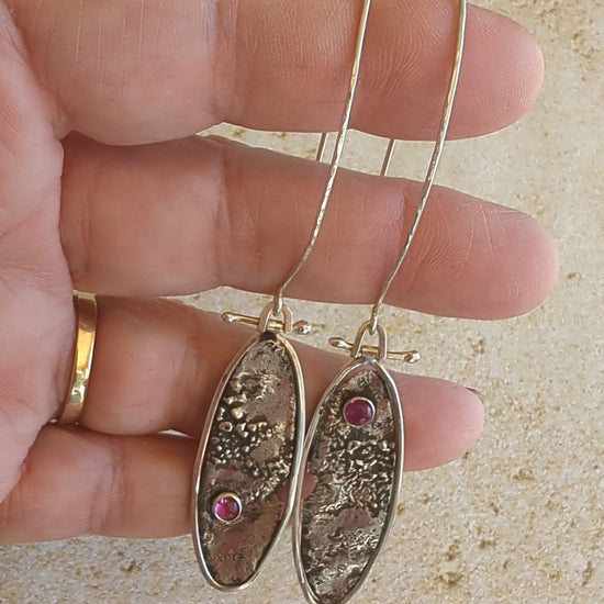 video of hand holding silver oval earrings