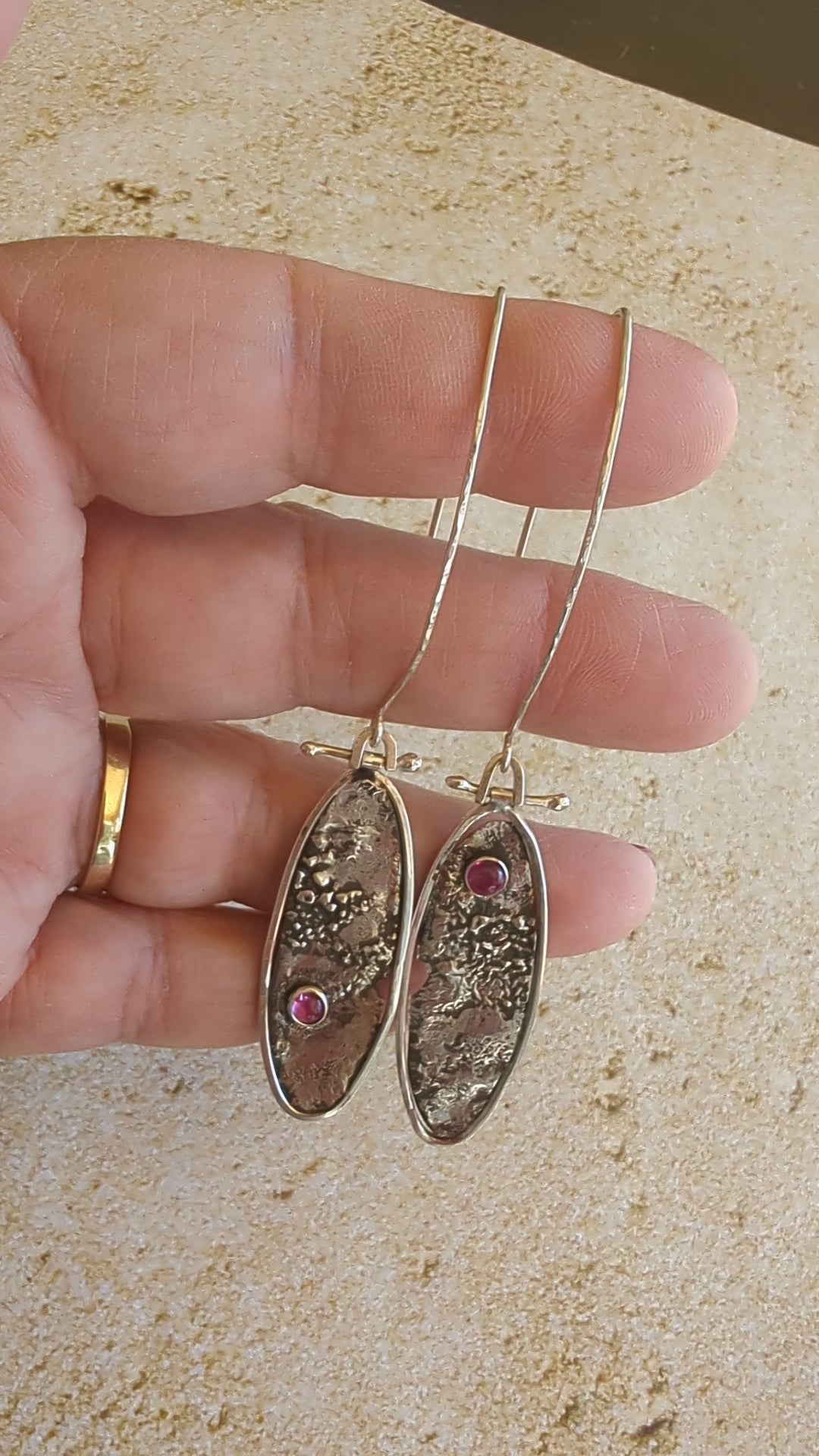 video of hand holding silver oval earrings
